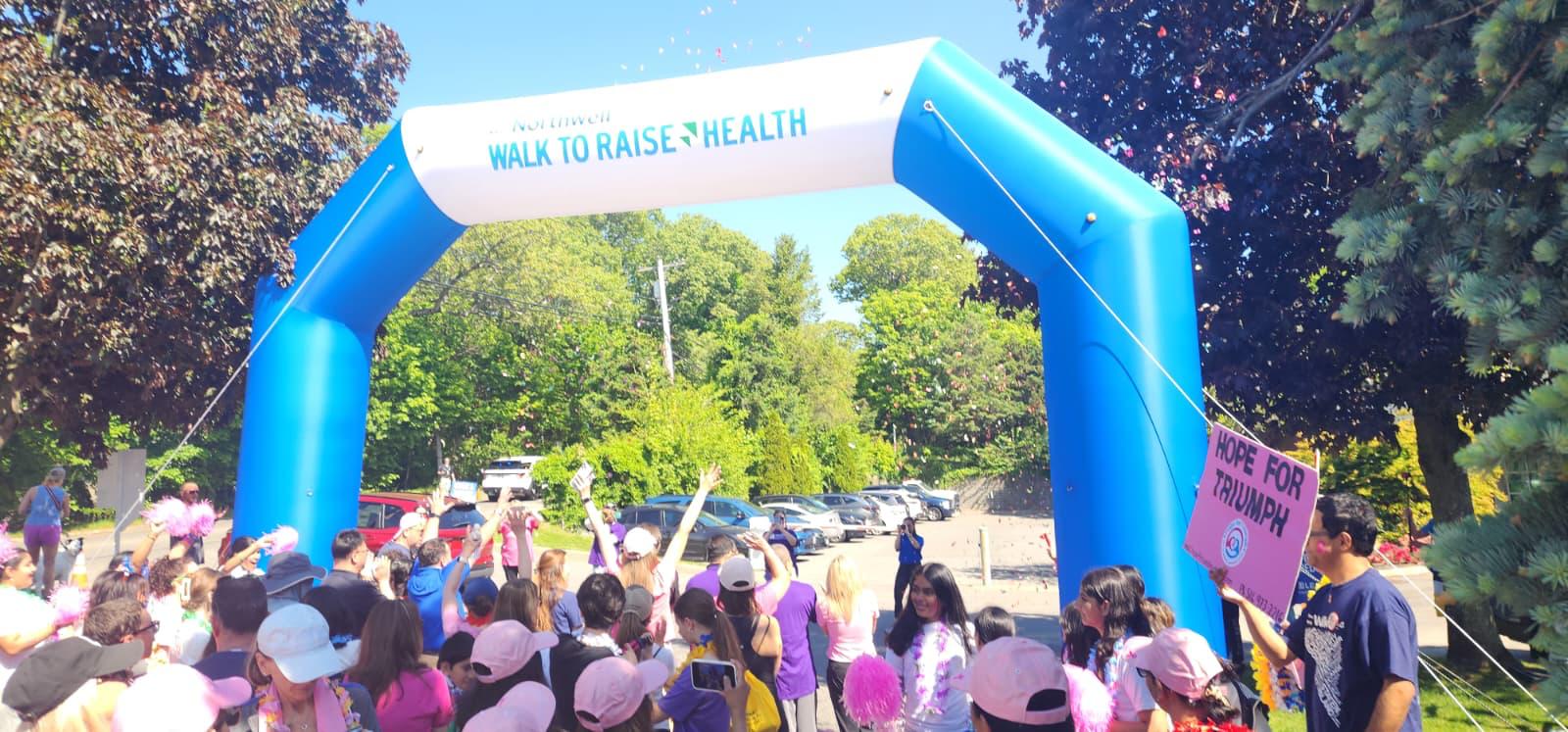 Walkers gathered under the Northwell Walk to Raise Health arch holding a Hope For Triumph sign